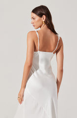 A woman is wearing a sleeveless satin slip dress in white, featuring thin adjustable spaghetti straps.