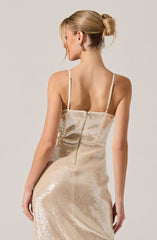 A woman is wearing a fitted, sleeveless, floor-length gown made of shimmering, light-colored sequined fabric. The dress features thin spaghetti straps and a center back zipper.