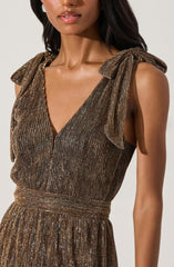 A woman wearing a sleeveless dress with a metallic, glittery fabric featuring vertical stripes. The dress has shoulder ties that form bows, and a fitted, elastic waistband.