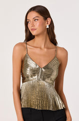 A young woman is wearing a metallic gold, pleated, sleeveless top with thin spaghetti straps. The top features a central zipper detail and has a slightly flared, ruffled hem. She is paired with black bottoms and accessorized with large, white, geometric-shaped earrings.