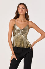A woman is wearing a shiny, metallic gold sleeveless top with thin spaghetti straps. The top features a ruched design on the bust and a peplum hem with vertical pleats that flare out at the waist. She pairs it with black pants. She accessorizes with geometric silver earrings and a silver bracelet.