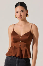 A woman is wearing a brown satin sleeveless top with thin spaghetti straps. The top features a sweetheart neckline, three decorative gold buttons down the front, and a pleated hem that flares out slightly.