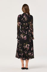 The dress is a long, flowy black garment with a floral pattern featuring pink, purple, white, and green colors. It has long, semi-sheer sleeves and a high neckline. The overall style is elegant and suitable for formal or semi-formal occasions.