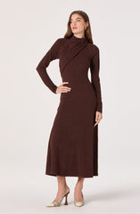 The woman is wearing a long, dark brown dress with a high neckline and long sleeves. The dress has a fitted waist and a slightly flared hem that reaches just above her ankles. She is also wearing a pair of beige and cream patterned high-heeled shoes.