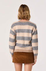 A person is wearing a long-sleeved, crew neck sweater with wide horizontal stripes in beige and gray. The sweater appears soft and cozy. They are also wearing a brown corduroy skirt that is above the knee.