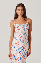 A woman is wearing a sleeveless, spaghetti strap dress with a white background. The dress is decorated with various colorful text and graphic elements in red and blue, including words like "Gelato," "Summer," and "Vitamin." The overall style of the dress is casual and summery.