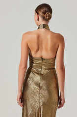 A woman is wearing a strapless, metallic gold evening gown with a fitted bodice. The fabric has a shiny, textured appearance, and the dress features a high neckline and a zipper closure at the back.
