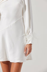 A person is wearing a white satin dress with long sleeves. The dress features a slight asymmetrical design and has decorative feathers at the ends of the sleeves.