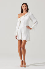 A woman is wearing a white, off-the-shoulder dress with long sleeves. The dress has a draped neckline on one shoulder and sheer, feathered cuffs on the sleeves. The skirt is short and slightly flared. She pairs the dress with white high-heeled sandals.