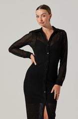 A woman is wearing a long black dress made of a sheer, textured, see-through fabric. The dress features a button-up front with small black buttons, a classic collar, and long sleeves. The fabric appears lightweight with a perforated pattern, giving it a delicate and breathable appearance.