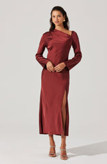 The woman is wearing a long, satin burgundy dress. The dress features a boat neckline with a draped design across the chest, long sleeves, and a high slit on one side revealing her leg.
