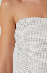 A close-up of a person wearing a strapless top made of white fabric with small, evenly spaced shiny embellishments, creating a textured, dotted pattern. The top fits snugly and the person's skin is visible on the shoulder and upper arm.