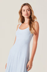 A woman is wearing a sleeveless, light blue, ribbed dress with a scoop neckline. The dress features vertical ribbing throughout, creating a textured appearance, and extends down past her hips.