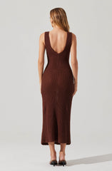 A woman is wearing a fitted, sleeveless crochet dress in shades of brown and maroon. The dress has a deep scoop back and reaches down to her ankles, with open-toe high heels.