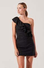 A woman is wearing a black one-shoulder mini dress with a large ruffle detail on the shoulder.