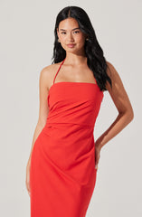 A woman is wearing a fitted, sleeveless, red dress with thin spaghetti straps. The dress has a straight neckline and a smooth, slightly gathered bodice. The fabric appears to be structured and elegant, draping smoothly down to her hips.
