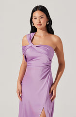 A woman is wearing a sleeveless, lavender satin dress with an off-the-shoulder design on one side. The dress features a twisted knot detail at the shoulder and a thigh-high slit on the side.