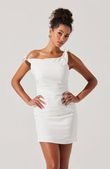 A woman is wearing a white, form-fitting dress that features off-the-shoulder sleeves tied into small bows on each shoulder. The dress is smooth and has a slightly gathered design at the waist.