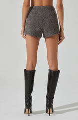 A person is wearing high-waisted, tailored shorts made of a textured, woven fabric in shades of gray and brown. They are also wearing tall, black leather knee-high boots with stiletto heels.