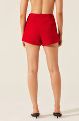 A person is wearing high-waisted red shorts made of a textured, fuzzy fabric. The shorts have a simple, clean design with no visible pockets or embellishments. The person is standing on a plain, neutral background, and their upper body is not visible.