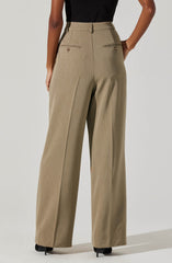 A person is wearing high-waisted, wide-leg beige trousers with a subtle plaid pattern. The trousers have front belt loops and two horizontal zippered pockets with small button accents. The person is also wearing a black top tucked into the trousers.