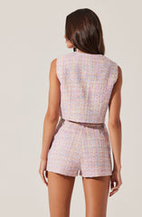 A woman is wearing a sleeveless, pastel-colored, textured two-piece outfit consisting of a boxy crop top and high-waisted shorts. The fabric appears to be a woven, tweed-like material with a soft, multicolored pattern.