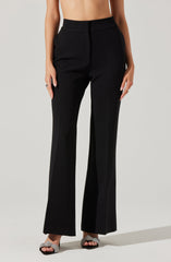 A person is wearing high-waisted, wide-leg black pants with a tailored fit. The pants have a smooth waistband and a front hook closure. They feature vertical seams running down the front of each leg and have a slightly flared, full-length hem. The person is also wearing open-toed high-heeled sandals with a sparkly, textured strap.
