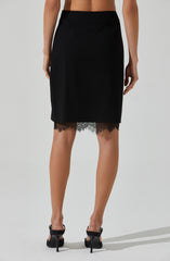 A woman is wearing a black skirt with a lace trim at the hem. The skirt is high-waisted and falls just below the knees. She is also wearing black high-heeled sandals.