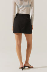 The image shows a person wearing a long-sleeved, ribbed, beige sweater tucked into a high-waisted black mini skirt. They are also wearing black open-toe sandals with a small heel.