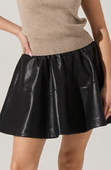 A person is wearing a beige knit sleeveless top with a fitted waistband and a black, shiny, faux leather A-line skirt with an elastic waistband.