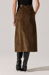 A person is wearing a high-waisted, long brown corduroy skirt with large back patch pockets. They have paired it with knee-high black leather boots with pointed toes and stiletto heels, and a black top tucked into the skirt.