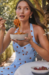A woman is wearing a light blue dress with large brown polka dots.