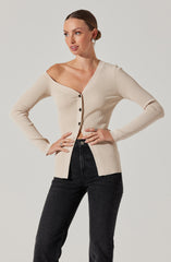 A woman is wearing a beige, ribbed, long-sleeve cardigan with a deep V-neckline and black buttons down the front. She has paired it with high-waisted black jeans.
