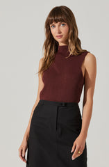 A woman is wearing a sleeveless, ribbed, high-neck top in a deep burgundy color with subtle vertical stripes and seam detailing on the front. She pairs it with a high-waisted black skirt that has a front button and two horizontal pocket flaps.