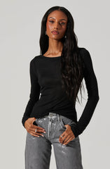 A woman is wearing a fitted black long-sleeve top with a crew neckline and shiny silver-gray pants with a high waist and relaxed fit. The outfit appears casual yet stylish.