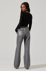A woman is wearing a fitted black long-sleeve top and high-waisted, loose-fitting gray jeans with a slightly faded and distressed look. The jeans feature large back pockets and a wide-leg cut.