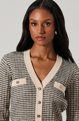 A woman is wearing a cream-colored cardigan with horizontal black and gray stripes. The cardigan features a V-neckline, cream-colored trim, and decorative buttons with diamond-like embellishments on the front pockets and center.