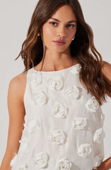 A woman is wearing a sleeveless white top decorated with three-dimensional flower appliqués.