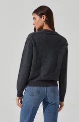 A woman is wearing a dark gray sweater with a ribbed hem and cuffs, and medium wash blue jeans with visible back pocket stitching.
