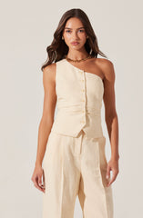 A woman is wearing a sleeveless, off-white, beige-colored vest with front buttons and matching high-waisted, wide-leg pants. The outfit appears to be made of a lightweight, textured fabric. She has accessorized with gold hoop earrings and a chunky gold chain necklace.