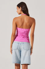 A woman is wearing a strapless, fitted pink top that has a halter neck style and appears to be made of a shiny, satin-like fabric. She is also wearing light-washed denim shorts with a relaxed fit, featuring two back pockets.