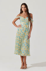 A woman is wearing a sleeveless, ankle-length dress with thin spaghetti straps and off-the-shoulder ruffle sleeves. The dress features a multicolored pattern in shades of yellow, blue, and white, with a fitted waist and a pleated skirt. She is also wearing strappy beige high-heeled sandals.