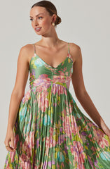 A woman wearing a sleeveless, floral dress with spaghetti straps. The dress has a fitted bodice with a ruched front zipper detail and a full, pleated skirt that features a colorful, vibrant floral pattern with shades of pink, green, purple, blue, and yellow.