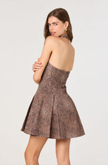 A woman is wearing a strapless dress with a leopard print pattern in shades of brown and black. The dress has a fitted bodice and a flared, A-line skirt. She is accessorized with large gold hoop earrings.