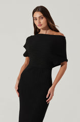 A woman is wearing a black, ribbed knit dress. The dress features a wide neckline that drapes off one shoulder, creating an off-the-shoulder look. The top part of the dress has horizontal ribbing, while the skirt has vertical ribbing, creating a contrast in the knit pattern. The dress is form-fitting and elegant.