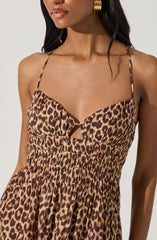 The outfit is a sleeveless dress with thin spaghetti straps. The fabric features a leopard print pattern with shades of brown, black, and tan. The bodice has a gathered design with a small keyhole cutout at the center, and the waist appears to be elasticized, creating a draped, gathered effect.