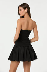 A woman is wearing a strapless black dress with a fitted bodice and a flared, gathered skirt.