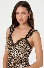 A woman is wearing a sleeveless top with a leopard print pattern. The top features black lace trim along the neckline and shoulder straps, which are tied into small bows. The overall style of the clothing combines animal print with delicate lace details.