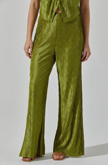 A person is wearing a matching set of shiny, textured olive green clothing. The top is sleeveless with buttons down the front and a small opening at the waist. The pants are high-waisted, wide-legged, and have a crinkled, shiny fabric that creates a textured appearance. The person is also wearing open-toed sandals and several rings on their fingers.