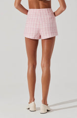 A woman is wearing high-waisted pink shorts with a textured, checkered pattern in light pink and white.